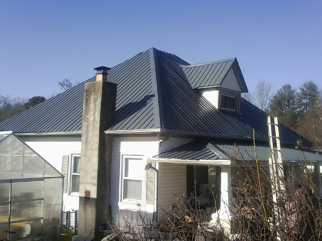 Dark blue standing seam metal roof on a white farmhouse with dormer — Slate & Tile Roof Repair by Roofing Brothers in Duryea