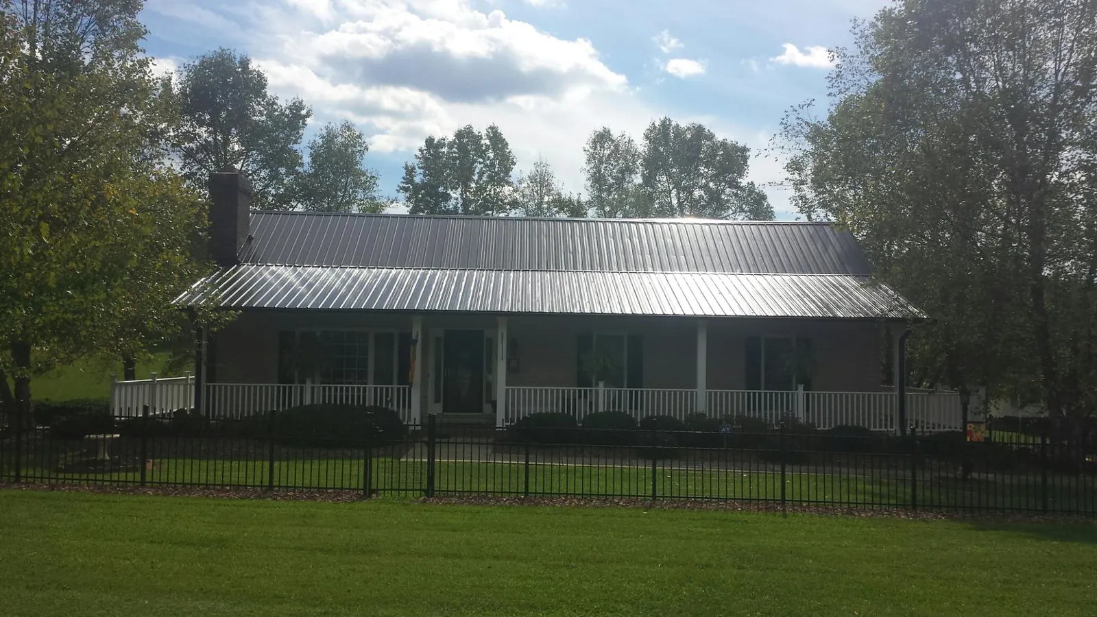 Gray metal roof on a brick ranch with a full width front porch — Gutter Guard Installation work by our crew in Duryea