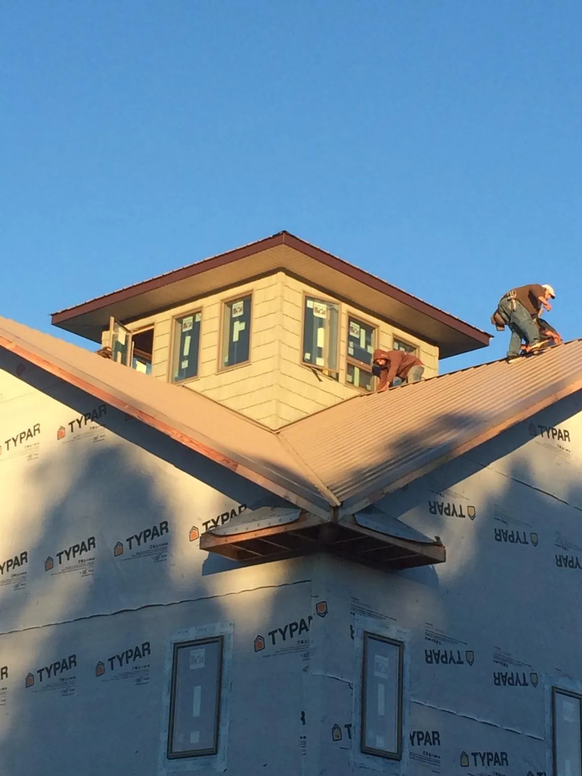 Roofers working around a rooftop cupola on a new metal roof at sunset — Roof Waterproofing in Duryea by Roofing Brothers